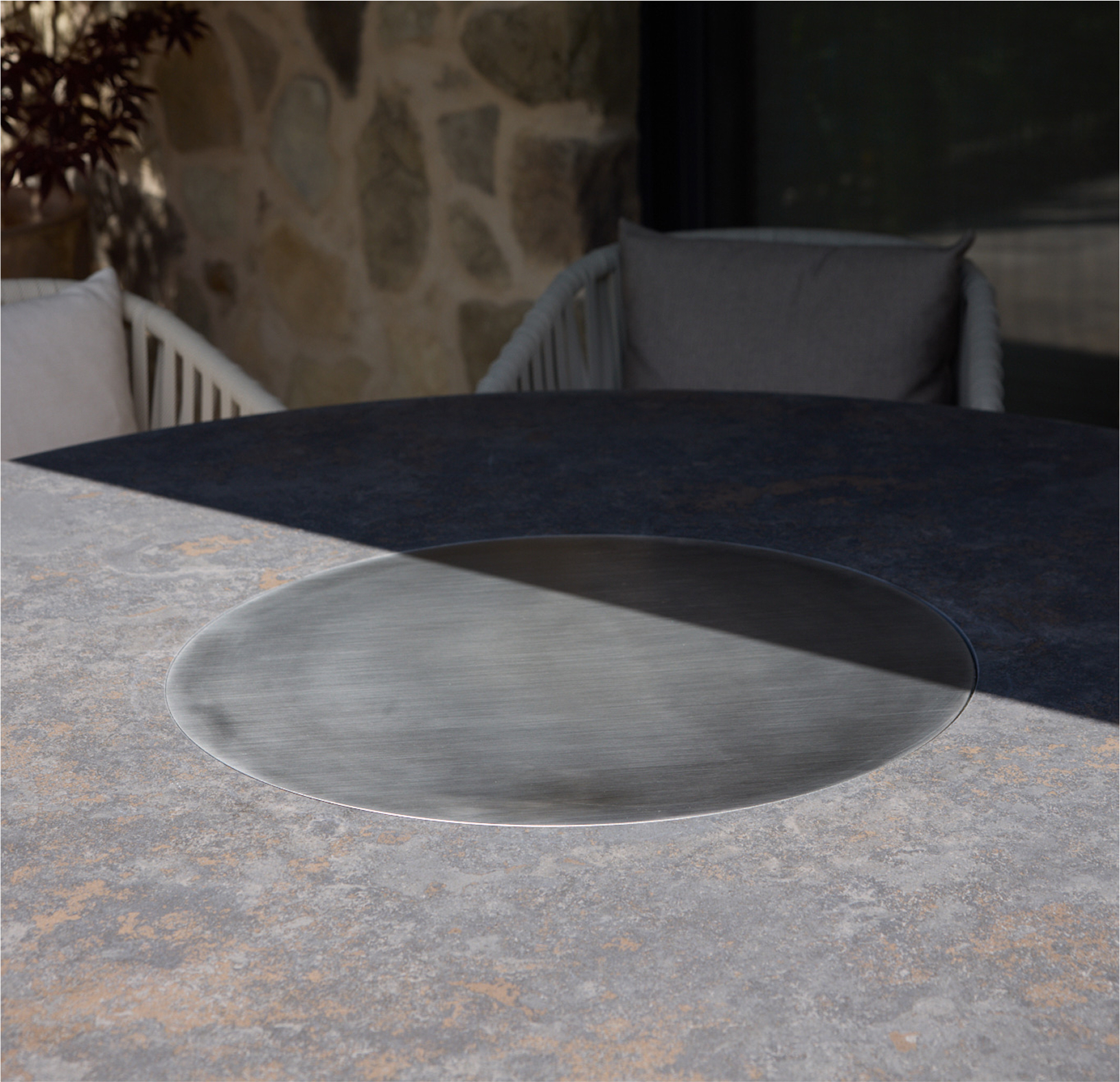 Ein moderner runder Tisch, einmal als Grill, einmal als Esstisch genutzt.